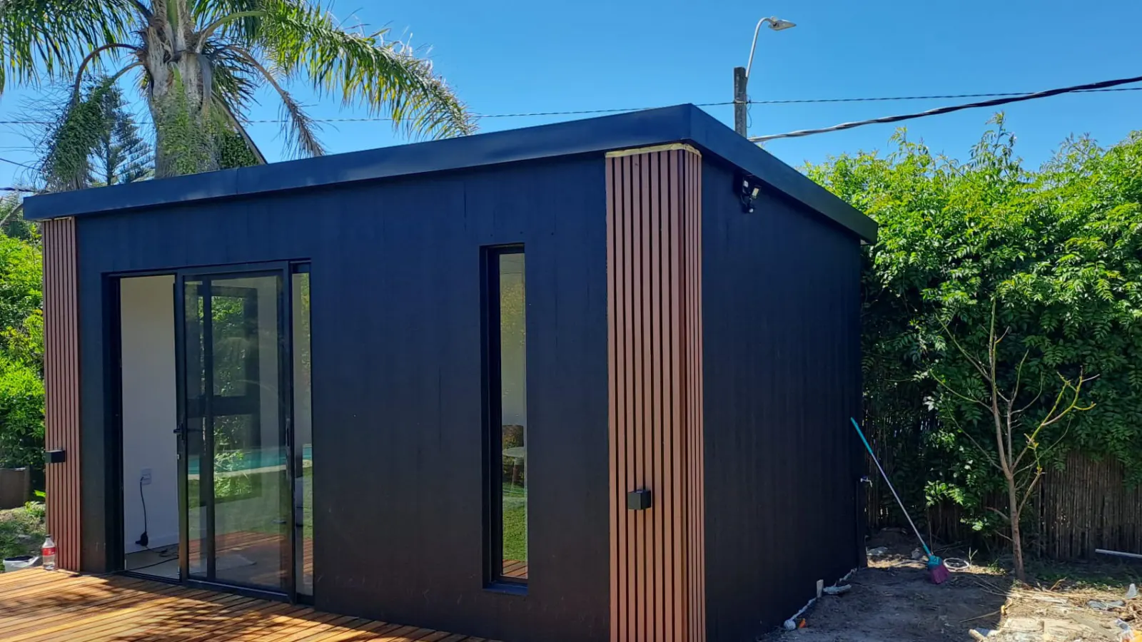 Modulo habitable terminado con revestimiento exterior negro y deck de madera